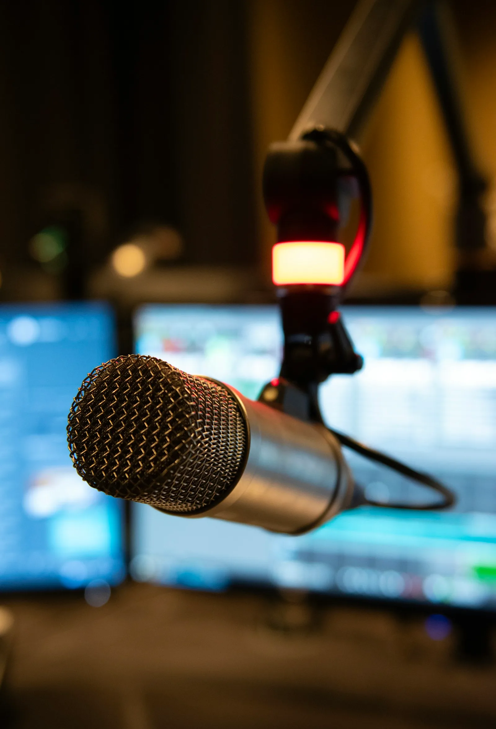 Close-up of a studio microphone with screens in the background