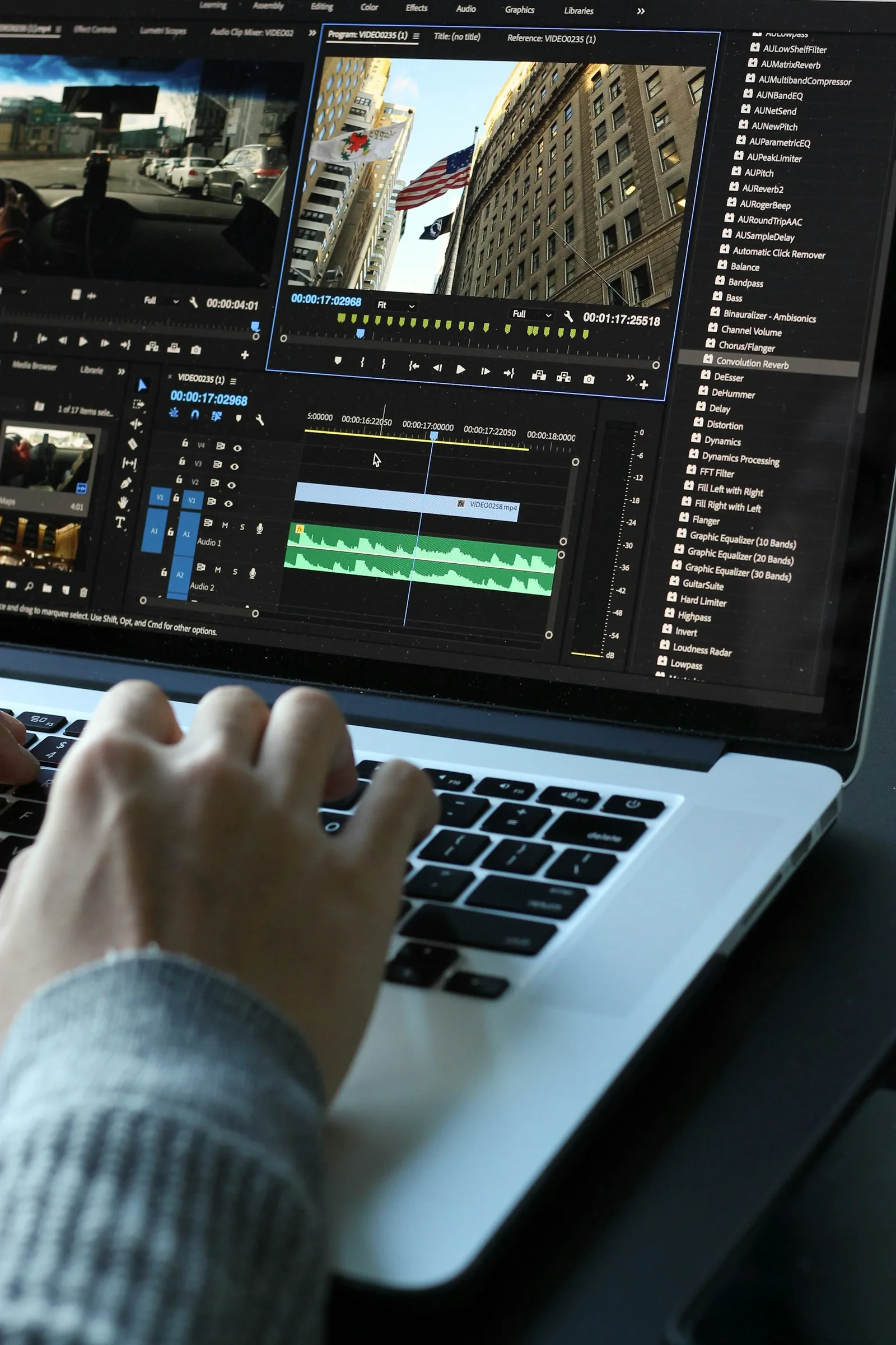 Person editing video and audio tracks on a laptop